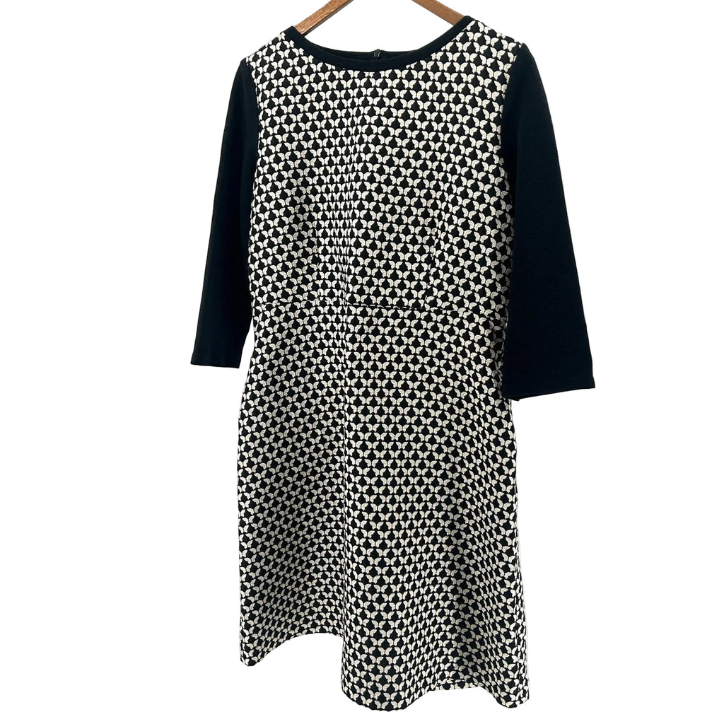 Black and white patterned dress on a hanger against a white background
