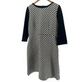 Black and white patterned dress on a hanger against a white background