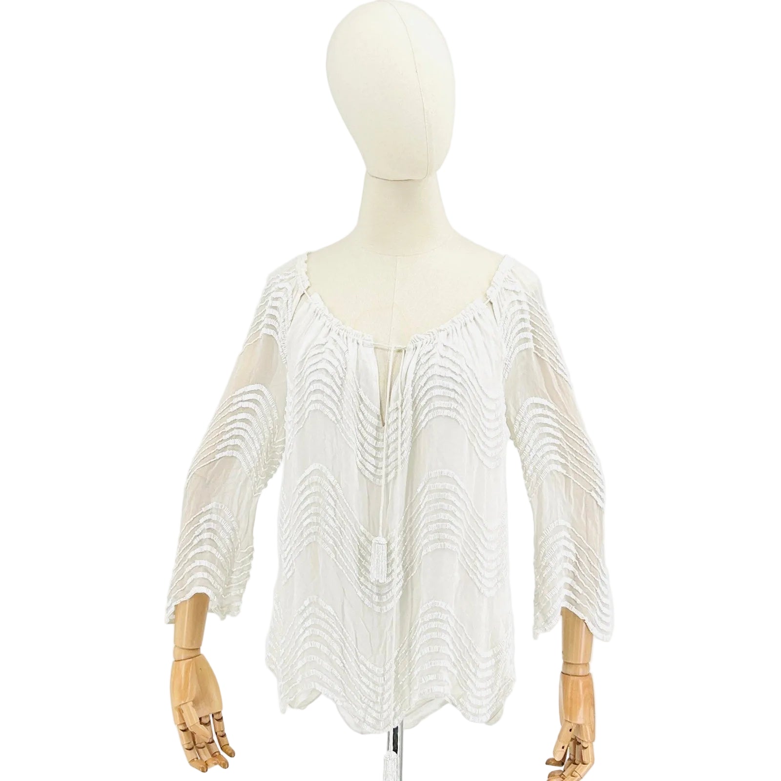 White fringe garment on a mannequin against a white background