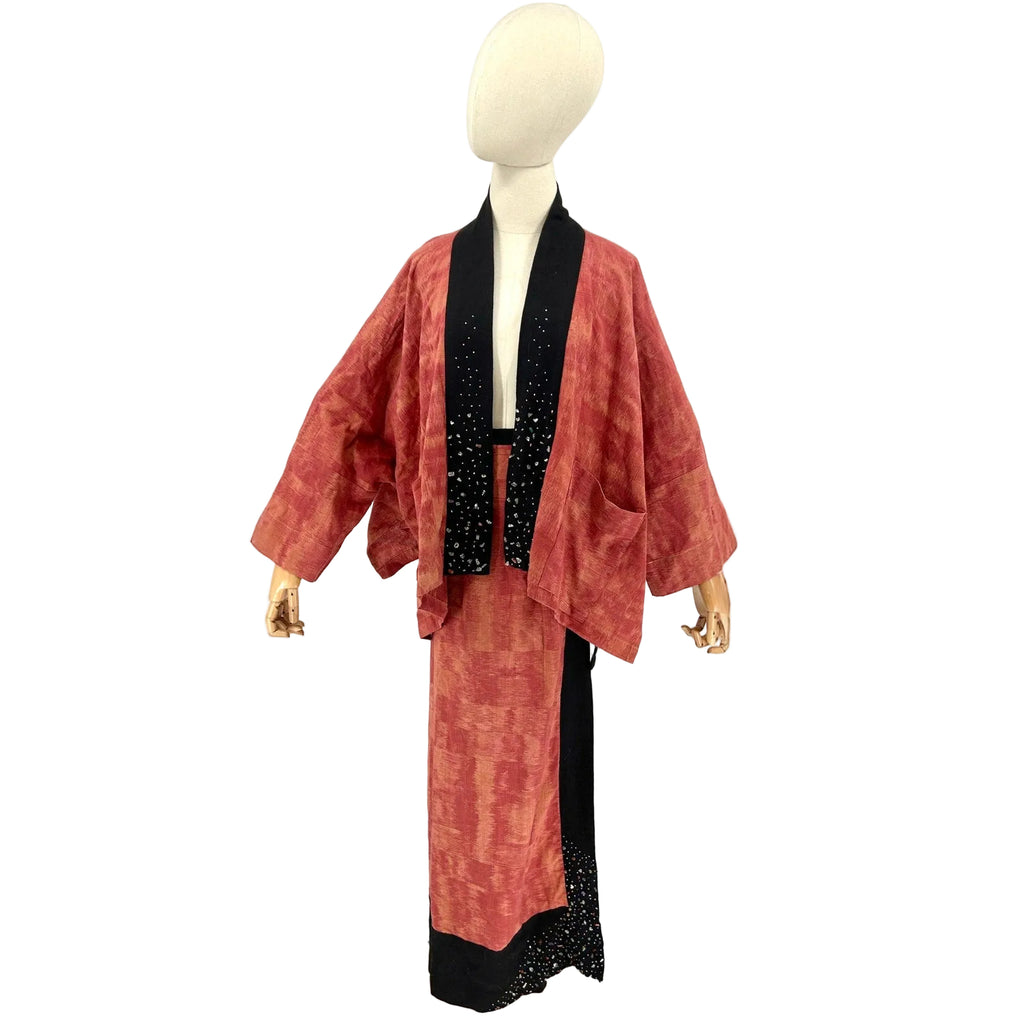 Mannequin wearing a red and black traditional outfit on a white background