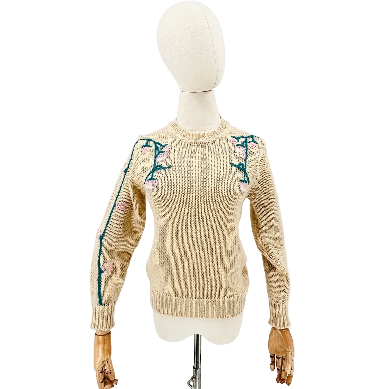 Beige sweater with floral embroidery on a mannequin against a white background